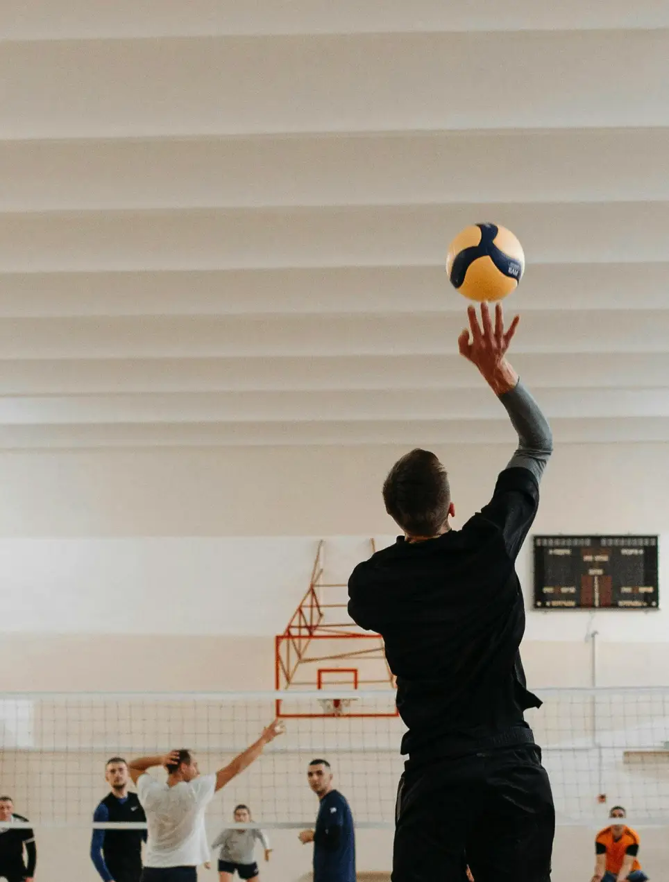 Mann beim Volleyballspiel in Sporthalle
