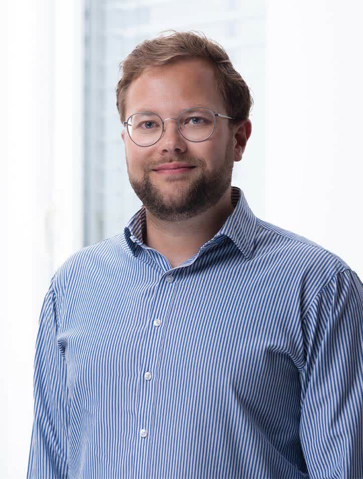 Person mit Brille und gestreiftem Hemd lächelt freundlich.