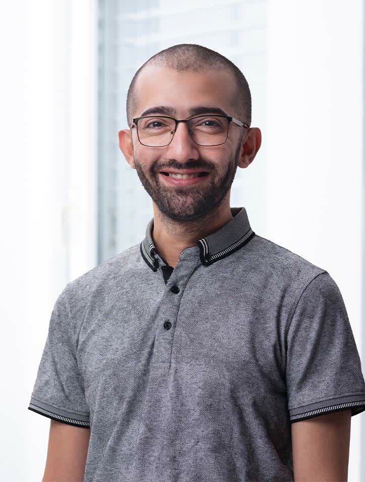 Lächelnder Mann mit Brille und grauem Hemd.